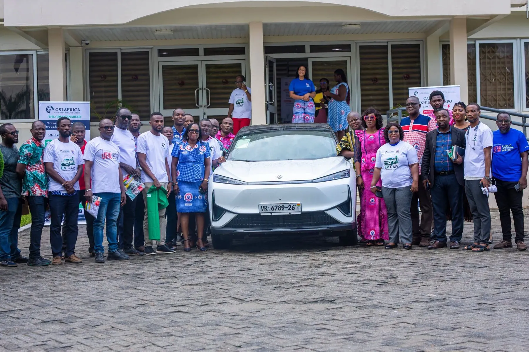 UEW staff and the GSI team gathered behind an electric SUV outside the Akwasi Asabere-Ameyaw building