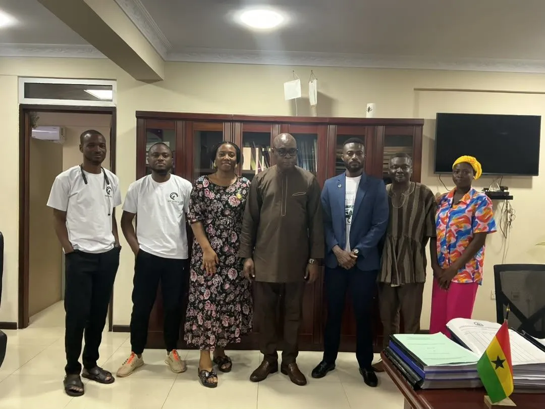 The GSI team standing with UEW officials in an office with the Ghana flag