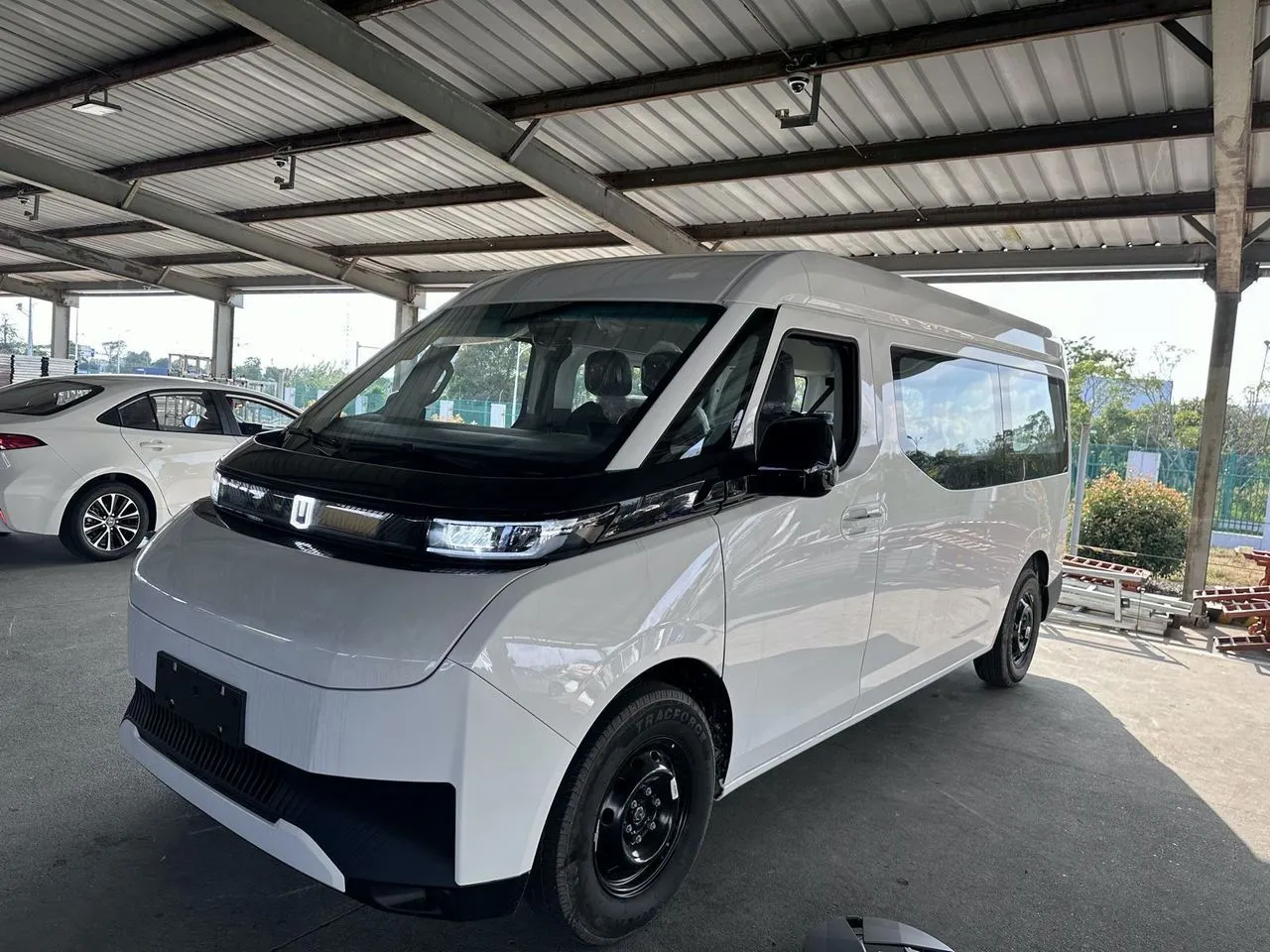 A white Joylong electric minibus at a supplier's yard